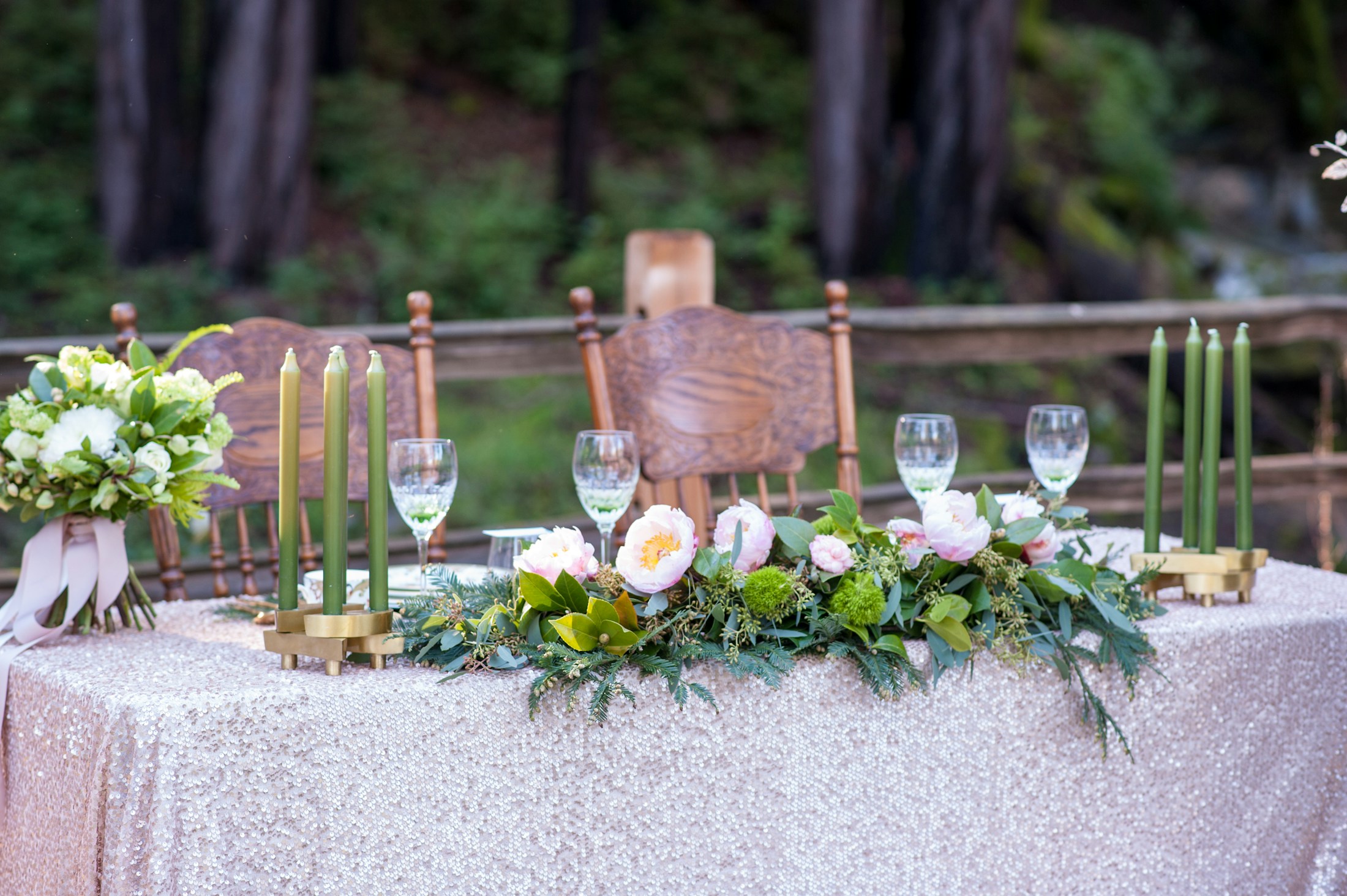 Mesa de boda con velas verdes, flores blancas y follaje